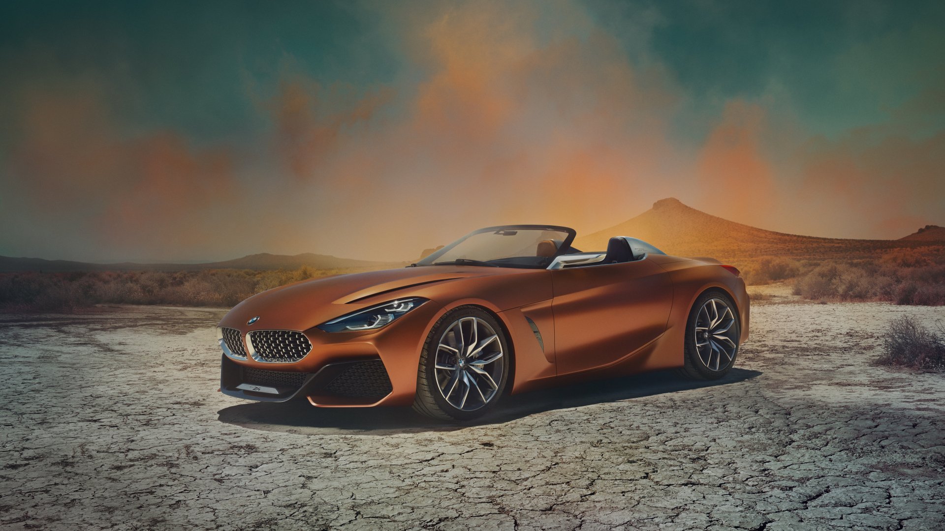 5K Ultra HD desktop wallpaper of an orange BMW Z4 convertible parked on cracked desert floor beneath a dramatic sky.