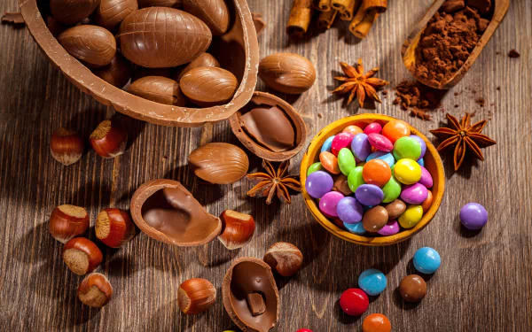 5K Ultra HD PC desktop wallpaper showing chestnuts, star anise, cocoa and broken chocolate shells with a bowl of colorful candy-coated sweets on a rustic wooden table.