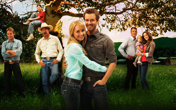 HD PC desktop wallpaper featuring the main cast of the TV show Heartland, set outdoors with characters posing in front of a large tree and open field background.
