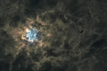 5K Ultra HD PC desktop wallpaper of the moon glowing through swirling dark clouds, a dramatic nature sky background.