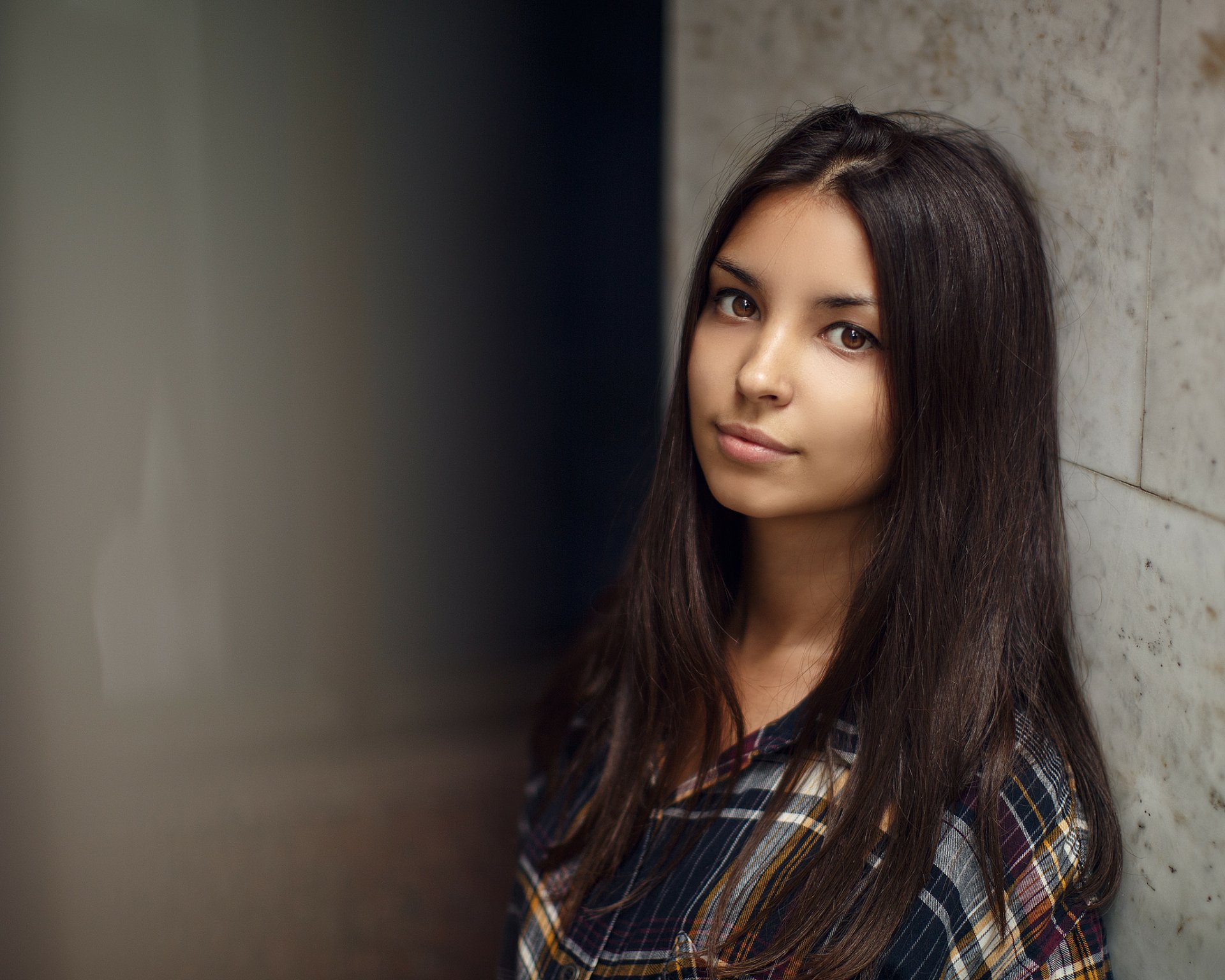 HD desktop wallpaper featuring a brunette woman with brown eyes posing against a neutral background, showcasing natural beauty and a calm expression.