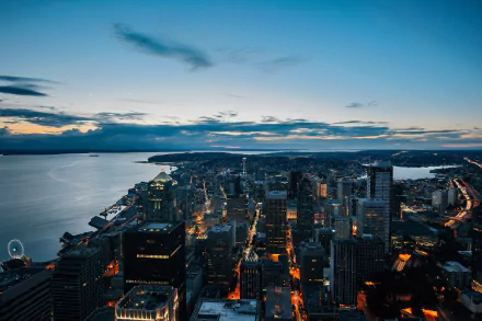 A stunning HD cityscape of Seattle, USA at dusk, featuring skyscrapers against a vibrant horizon over water, capturing the man-made urban skyline.