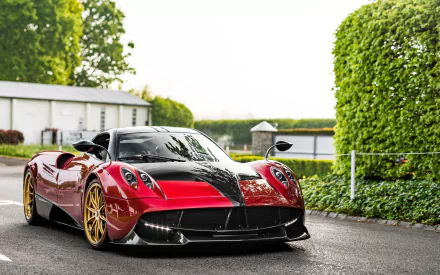 HD desktop wallpaper featuring a red and black Pagani Huayra supercar parked outdoors, showcasing its sleek design and golden wheels.