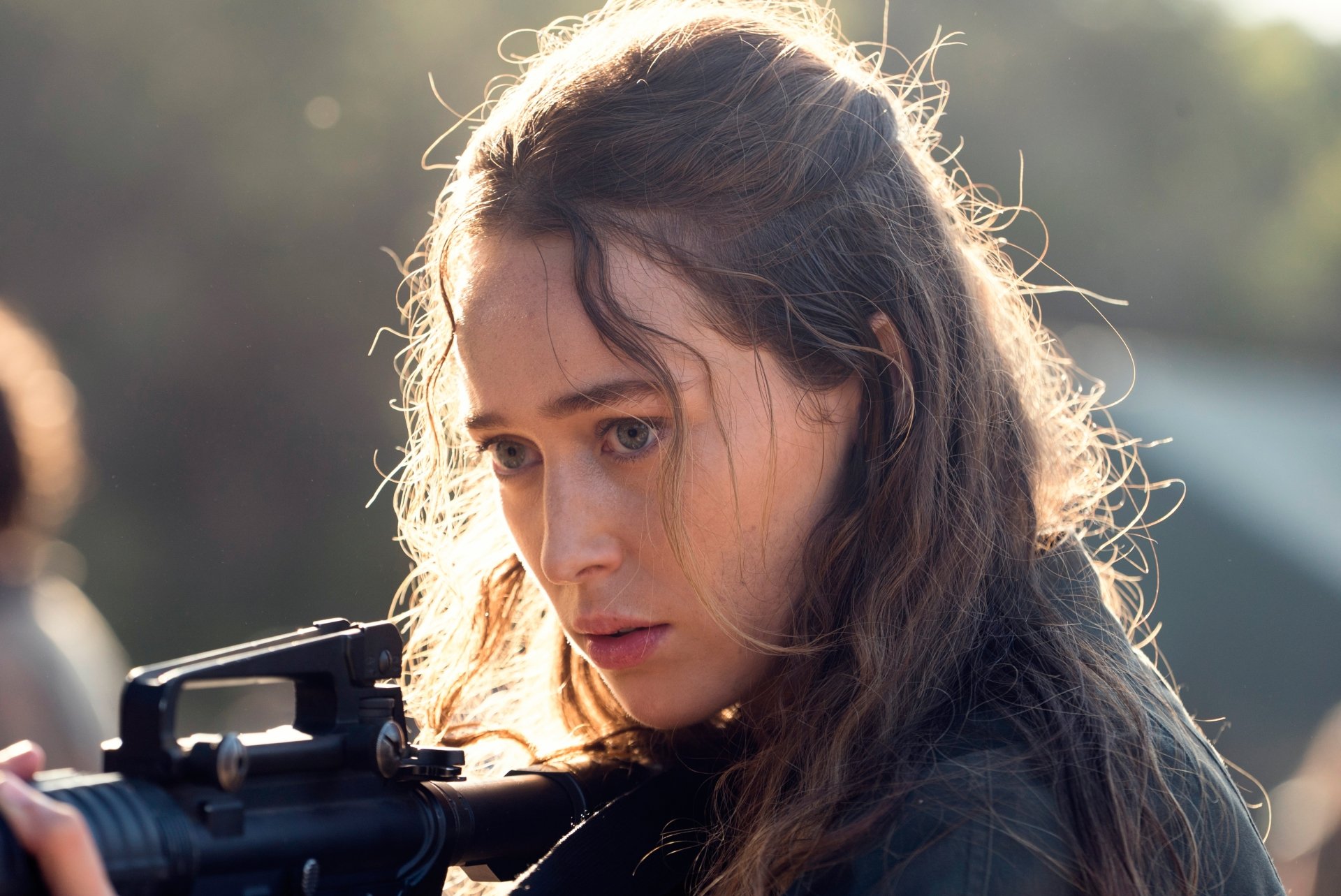 4K Ultra HD wallpaper of Alycia Debnam Carey as Alicia Clark from the TV show Fear the Walking Dead, focused and holding a weapon outdoors.