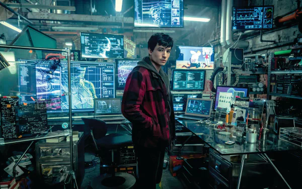 HD PC desktop wallpaper of Ezra Miller as Barry Allen, the Flash, from the 2017 Justice League movie, standing amidst a high-tech lab filled with monitors and equipment.