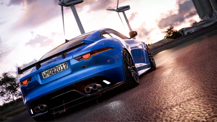 HD desktop wallpaper featuring a blue Jaguar F-Type from the video game Project Cars 2, showcasing the car in a sunset scene with wind turbines in the background.