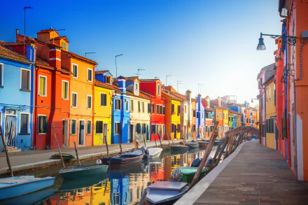 Colorful houses line a canal in Venice, Italy, with gondolas floating peacefully. This vibrant HD wallpaper captures the charm of this iconic city, offering a stunning desktop background.