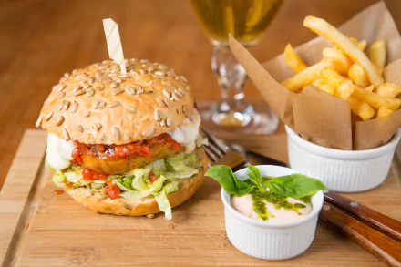 HD PC desktop wallpaper featuring a close-up of a burger with lettuce and tomato, accompanied by a side of golden French fries and dipping sauce.