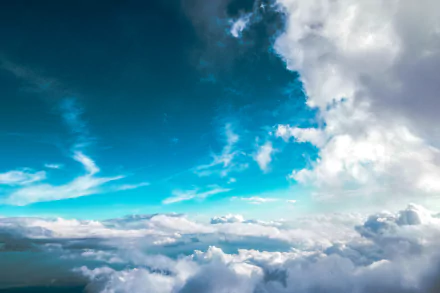 A breathtaking aerial view of the sky filled with fluffy clouds, captured in high definition. This nature-themed image showcases a vibrant blue sky and makes for a stunning desktop wallpaper or background.