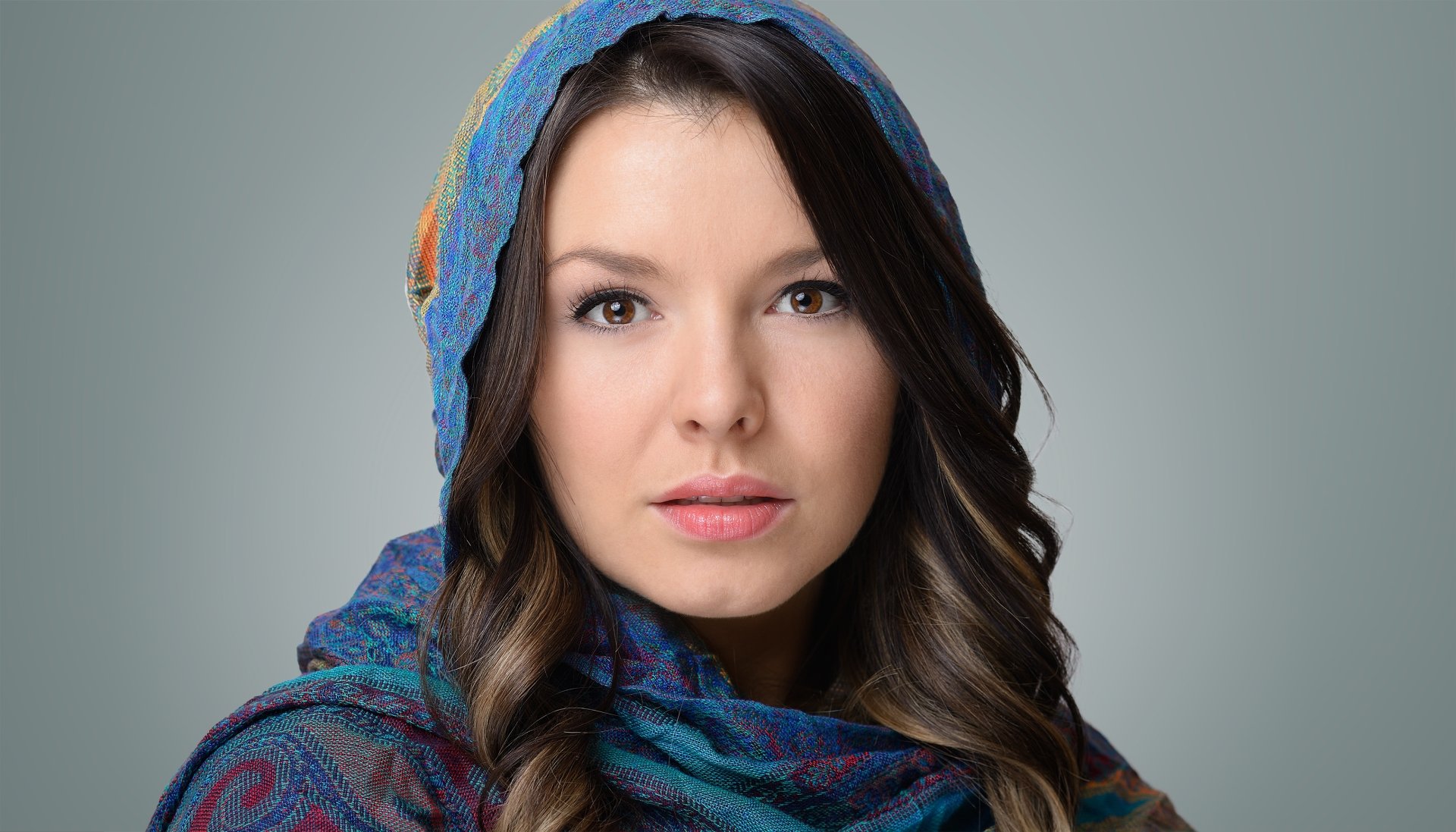 Close-up of a brunette model’s face with brown eyes and a colorful veil, captured as a 4K Ultra HD PC desktop wallpaper and background.