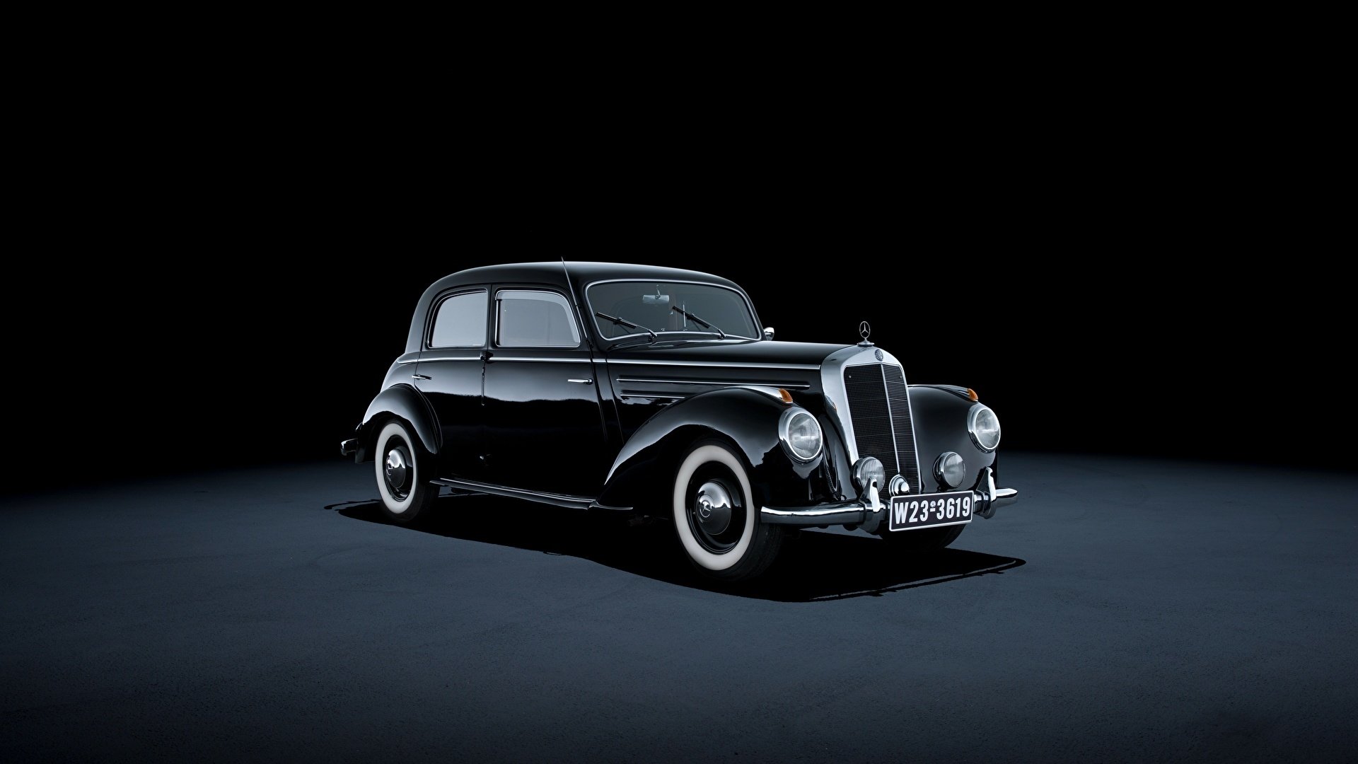 HD desktop wallpaper featuring a classic black Mercedes vehicle against a dark background, highlighting its vintage design and elegant curves.