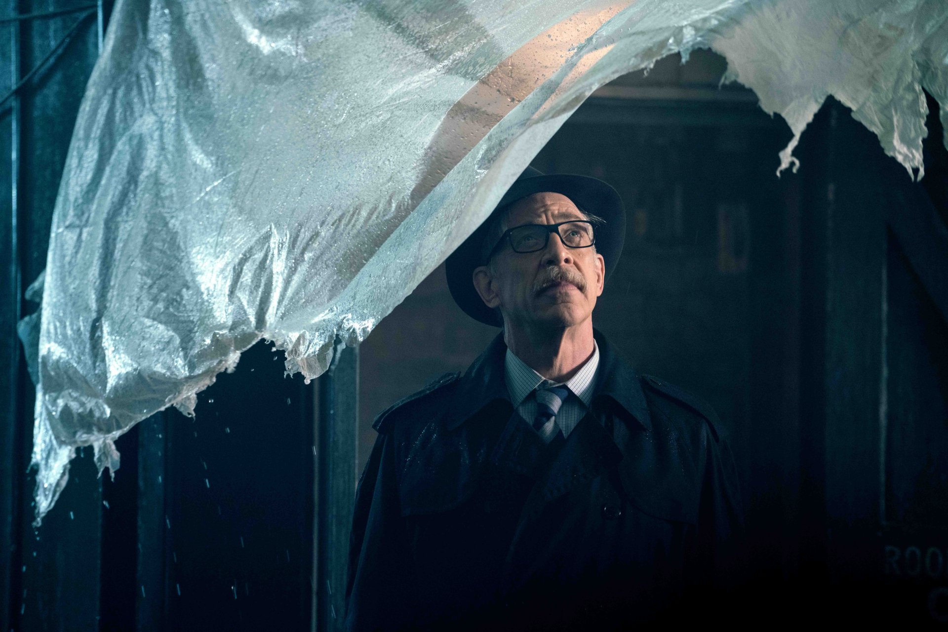 HD PC wallpaper featuring J.K. Simmons as Commissioner Gordon from the Justice League movie, framed through a torn plastic sheet in a dark, moody setting.