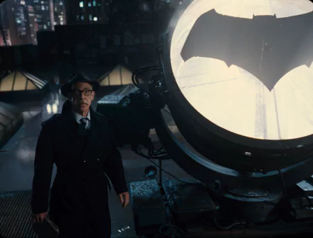 J.K. Simmons as Commissioner Gordon stands beside the illuminated Bat-Signal in a dark setting, from the Justice League movie, featured in an HD PC desktop wallpaper.