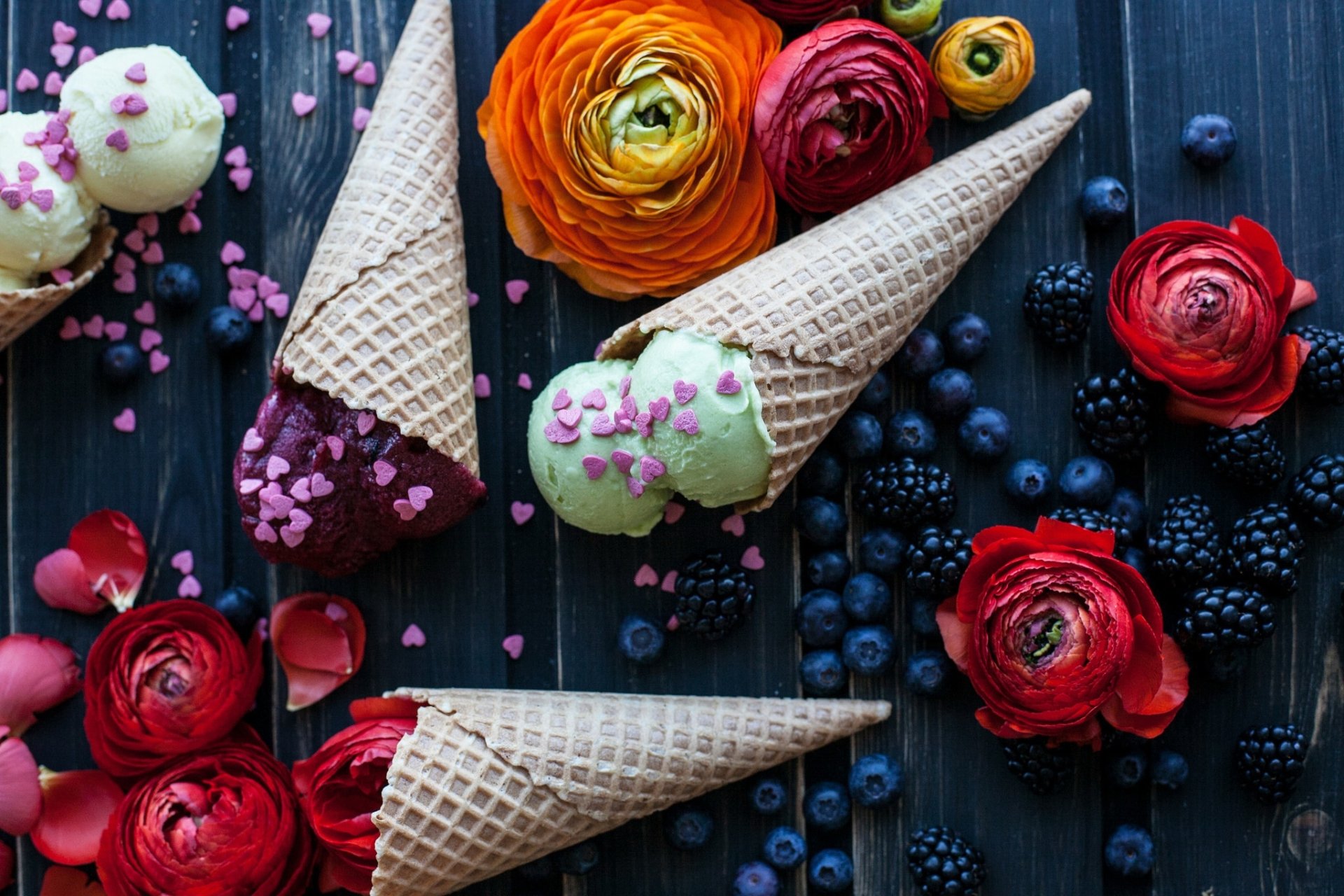 HD wallpaper of waffle cones with ice cream surrounded by blackberries, blueberries, and vibrant flowers, creating a colorful still life food scene.