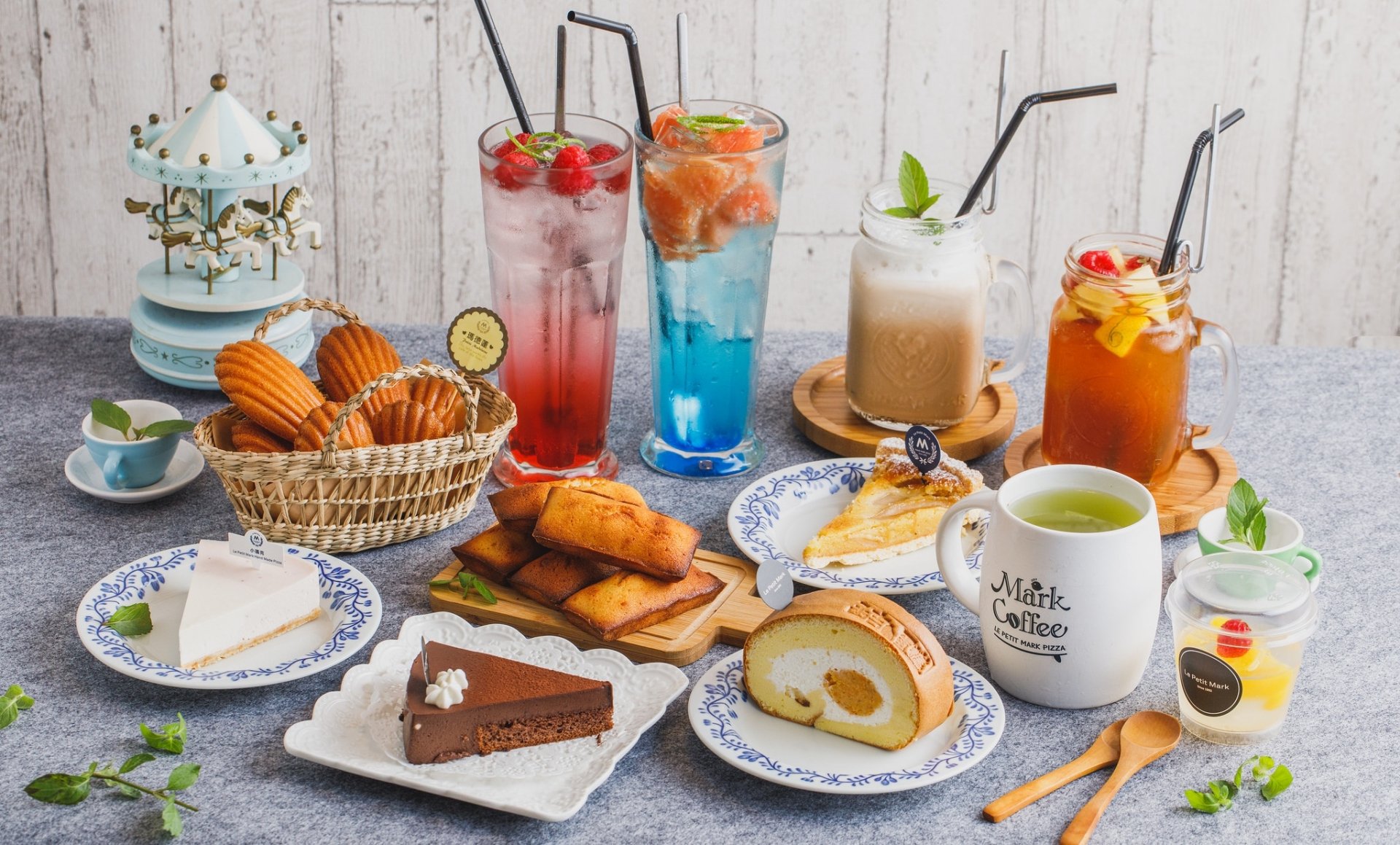 A vibrant still life HD desktop wallpaper featuring an assortment of cakes, desserts, and colorful cocktails and drinks arranged on a rustic wooden table.