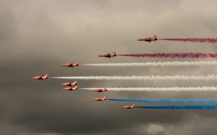 A formation of jet fighter aircraft releases colorful smoke trails during a military air show, captured as a striking HD desktop wallpaper and background.