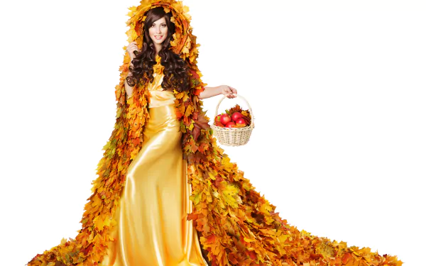 Brunette model in a flowing yellow dress and leaf cloak, smiling with brown eyes while holding a basket of apples — fall 5K Ultra HD PC desktop wallpaper background.