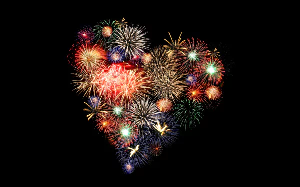 8K Ultra HD night photography of multicolored fireworks forming a glowing heart shape on a black background — PC desktop wallpaper.