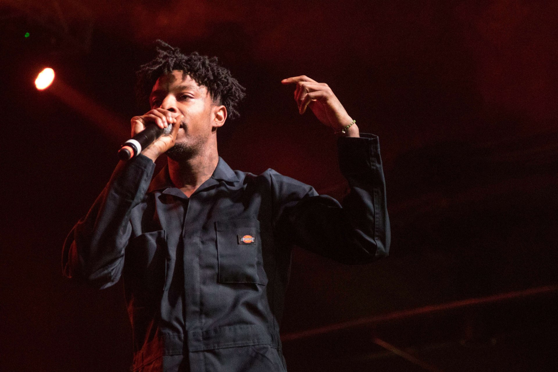 HD desktop wallpaper featuring a performer on stage with a microphone, with warm stage lighting in the background.