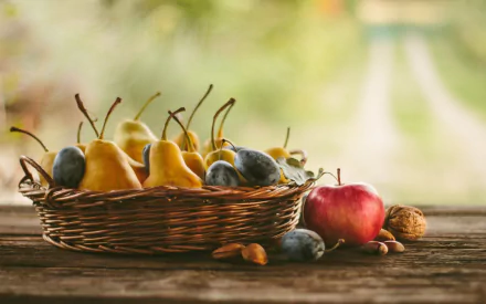 HD desktop wallpaper featuring a basket of fresh pears and plums, with a red apple and walnuts on a rustic wooden table, highlighting vibrant, natural fruit colors.
