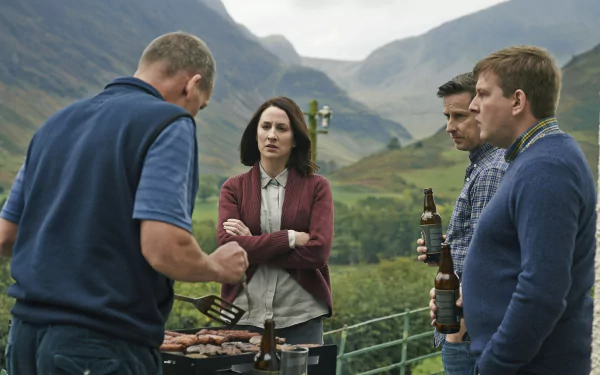 HD desktop wallpaper from The A Word featuring four characters in conversation by a barbecue with a scenic mountain backdrop.