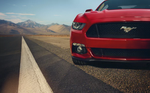 Close-up of a red Ford Mustang on an open road with mountains in the background, captured in stunning 8K Ultra HD for a vibrant PC desktop wallpaper.