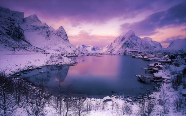 Dusk over a snowy mountain lake in Reine, Lofoten, capturing a vibrant purple sunset sky with clouds reflecting on the water in this HD winter landscape wallpaper.