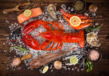 5K Ultra HD PC desktop wallpaper background still life: bright red lobster on crushed ice surrounded by shrimp, fish, oysters, lemon slices and seafood garnishes on a wooden board.