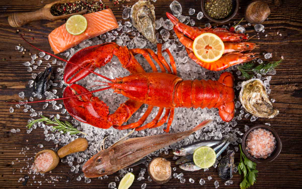 5K Ultra HD PC desktop wallpaper background still life: bright red lobster on crushed ice surrounded by shrimp, fish, oysters, lemon slices and seafood garnishes on a wooden board.