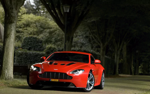 Red Aston Martin Vantage sports car parked under trees at night — HD PC desktop wallpaper and background showcasing the vehicle's sleek lines.