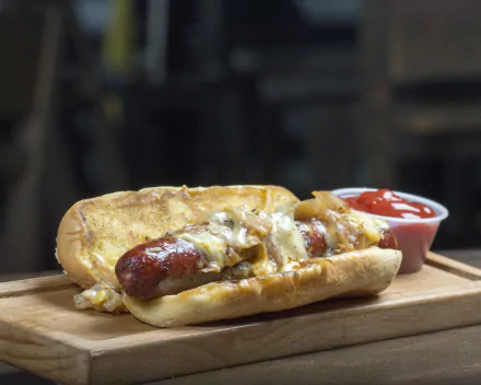 HD PC desktop wallpaper featuring a close-up of a hot dog topped with melted cheese, served with a side of ketchup on a wooden board.