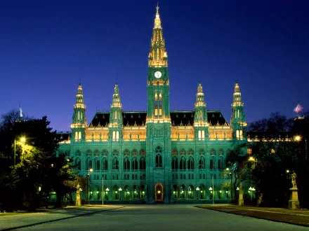 A stunning view of Vienna's City Hall illuminated at night. This striking man-made building showcases intricate architecture against a vibrant evening sky.
