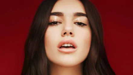HD desktop wallpaper featuring singer Dua Lipa with brunette hair and brown eyes against a red background.