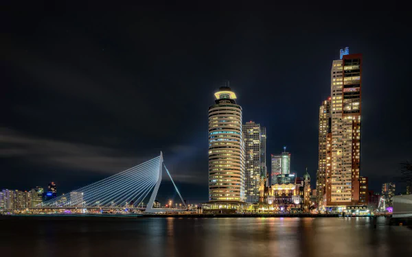 HD PC desktop wallpaper of Rotterdam, Netherlands night skyline: illuminated skyscrapers, lighted bridge and waterfront reflections showcasing modern man-made architecture.