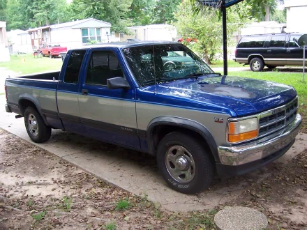 A Dodge Dakota truck parked on a driveway surrounded by greenery, featuring a blue and silver color scheme. This HD image serves as a striking desktop wallpaper or background.