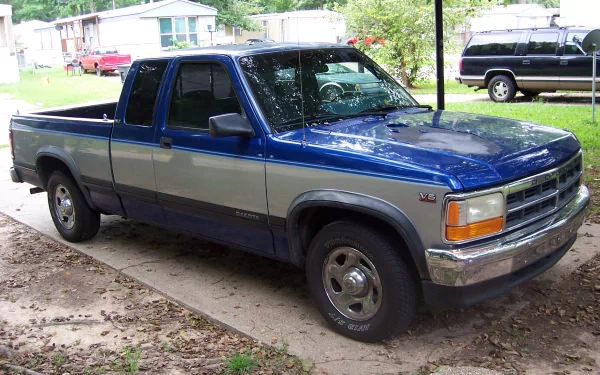 A Dodge Dakota truck parked on a driveway surrounded by greenery, featuring a blue and silver color scheme. This HD image serves as a striking desktop wallpaper or background.