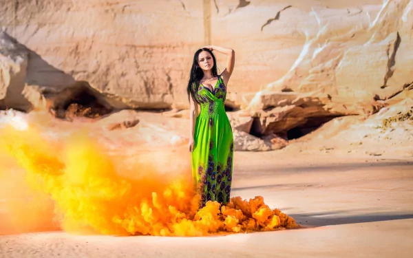 A black-haired woman in a green dress stands confidently on a sandy desert background with orange smoke swirling around her, captured in HD.