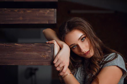 HD PC desktop wallpaper of a brunette model woman with hazel eyes and lipstick, leaning on a wooden railing in an intimate portrait against a dark background.
