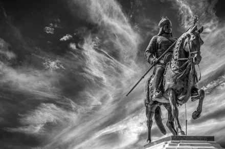 Black and white HD desktop wallpaper of a warrior statue on horseback, set against a dramatic cloud-filled sky, serving as a striking memorial.