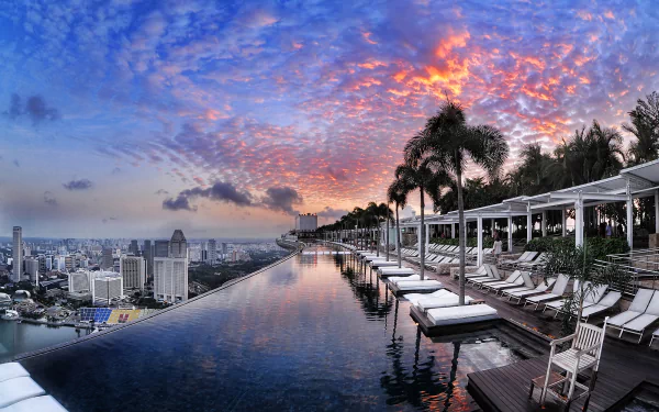 A stunning sunset over the city skyline and infinity pool at Marina Bay Sands, Singapore. This HD desktop wallpaper captures the luxurious ambiance of the hotel against a vivid evening sky.
