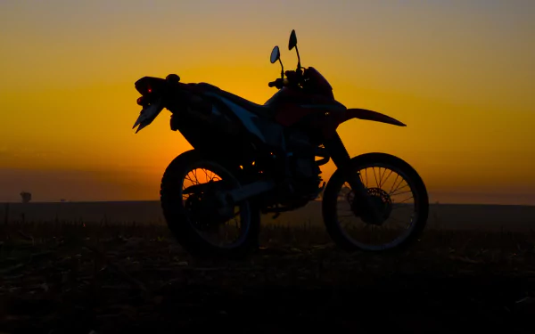 Silhouette of a Honda motorcycle against a golden sunset horizon — 4K Ultra HD PC desktop wallpaper/background showcasing a lone vehicle at dusk.