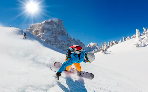 A snowboarder navigates fresh powder in a stunning winter mountain landscape, with bright sunshine illuminating the scene and showcasing the thrill of winter sports.