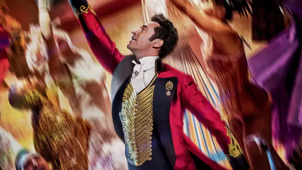 HD wallpaper of The Greatest Showman, featuring a performer in a vibrant ringmaster costume with an arm raised mid-performance.