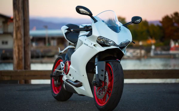 4K Ultra HD desktop wallpaper featuring a sleek white Ducati motorcycle parked by a waterfront at sunset.