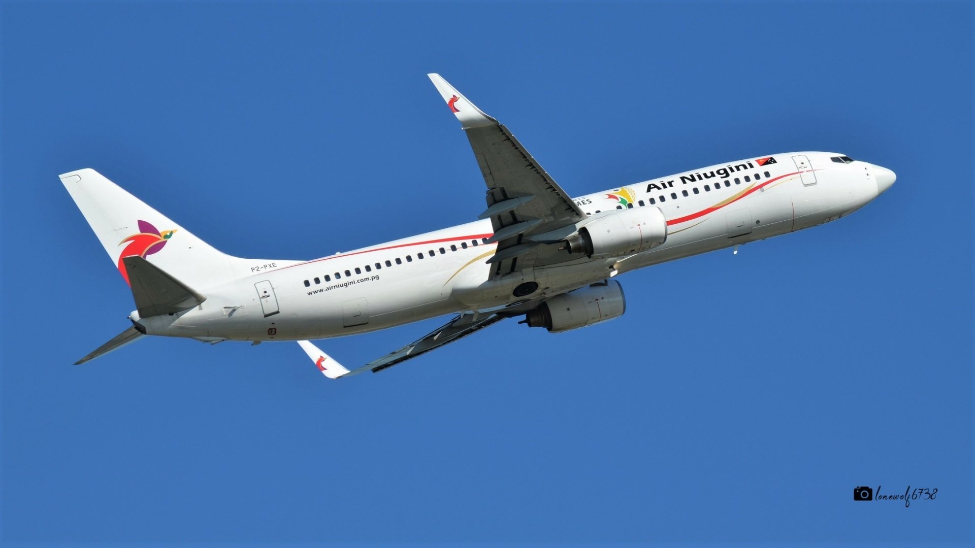 A Boeing 737 passenger aircraft from Air Hungary flies against a clear blue sky in this HD desktop wallpaper and background image.