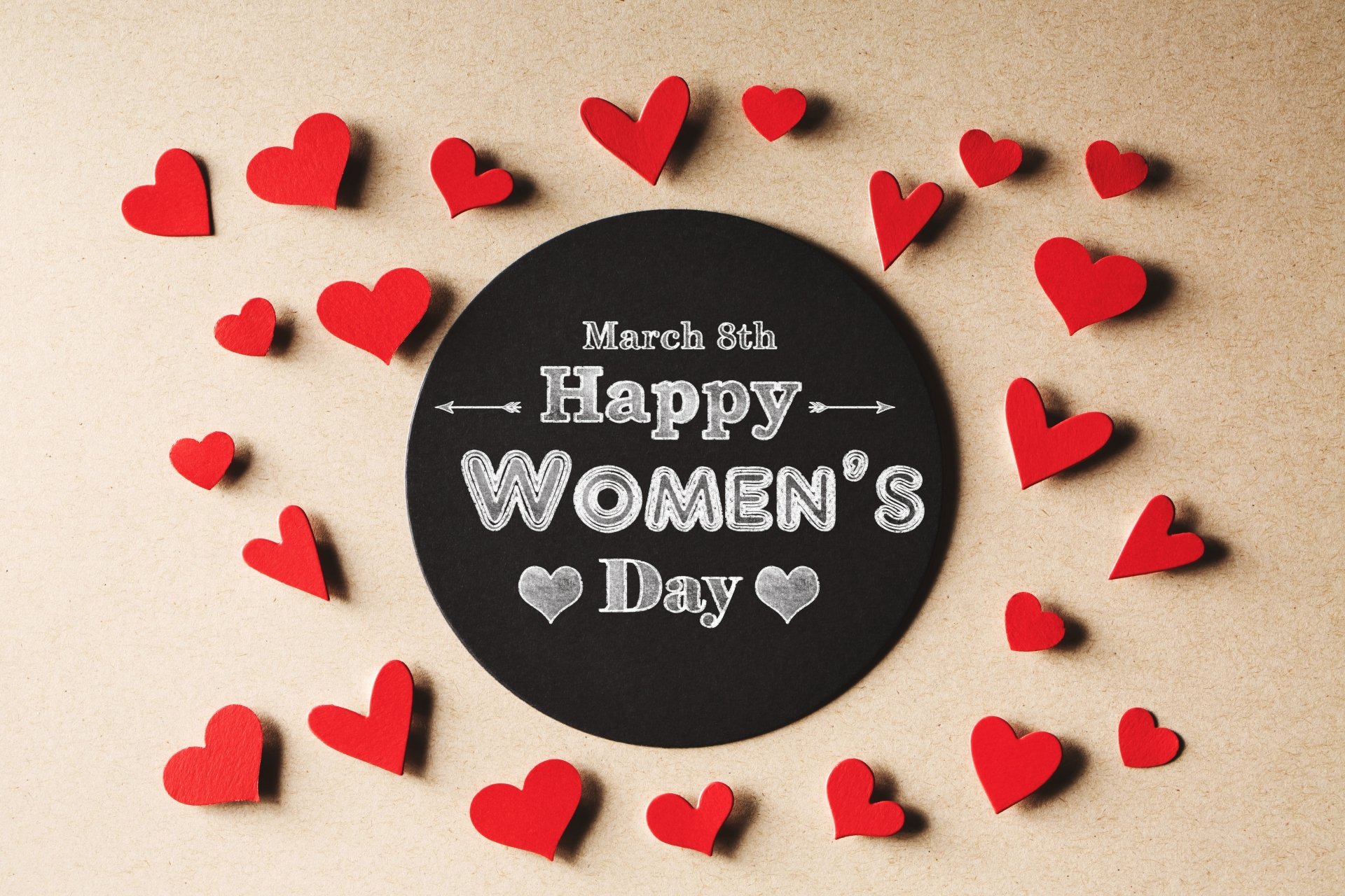 4K Ultra HD Women's Day desktop wallpaper featuring a black circle with March 8th Happy Women's Day surrounded by red hearts on a beige background.