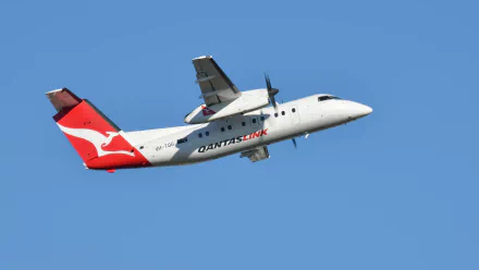 Passenger De Havilland Bombardier Dash 8 aircraft in QantasLink livery flying against a clear blue sky in this HD desktop wallpaper.