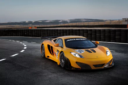 Orange McLaren MP4-12C supercar parked on a racetrack under a clear sky, captured in stunning 4K Ultra HD for a PC desktop wallpaper background.