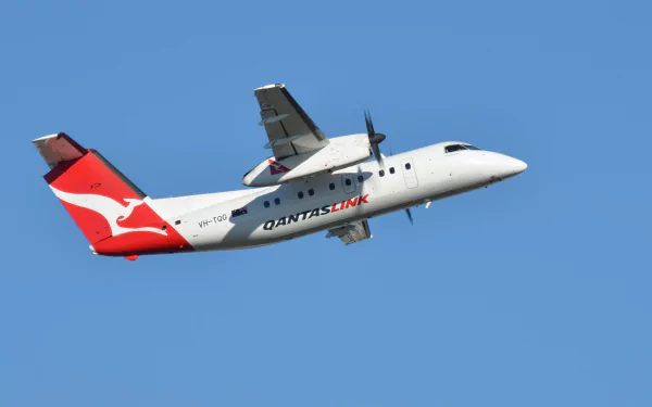 Passenger De Havilland Bombardier Dash 8 aircraft in QantasLink livery flying against a clear blue sky in this HD desktop wallpaper.
