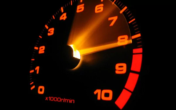 Close-up HD desktop wallpaper of a glowing vehicle speedometer highlighting the needle near the high RPM range, emphasizing speed and performance.